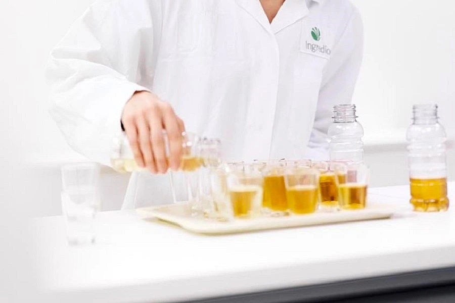 female scientist's hand pouring yellow liquid in small flasks in lab